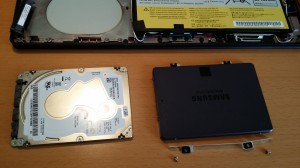 Old HDD left (with the foil and side strips removed) and new SDD right (with the far side strip attached and near strip ready to be screwed on).